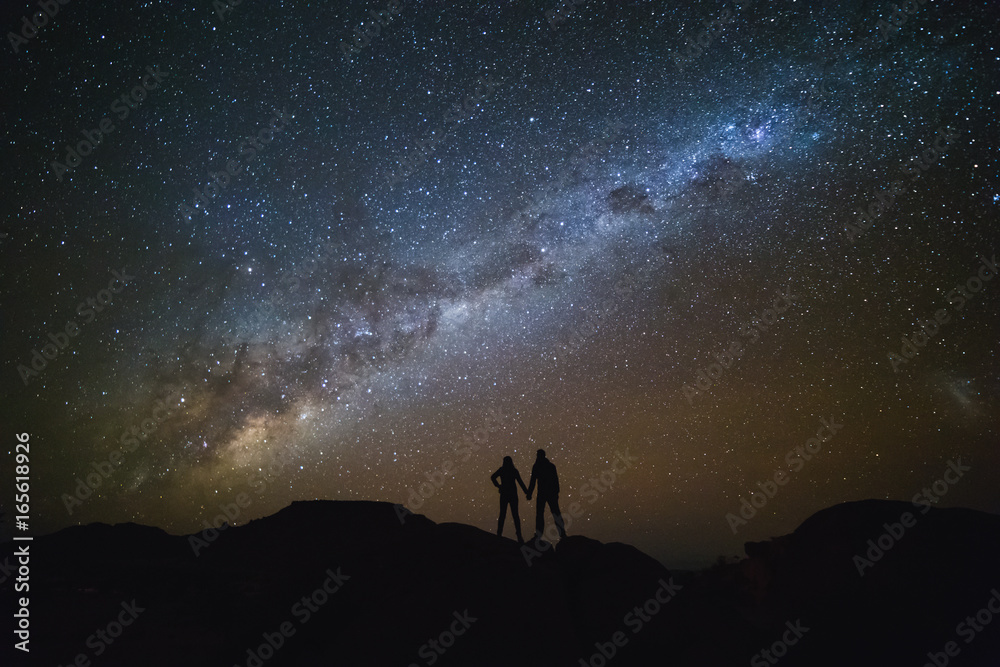 Landscape with Milky Way. Night sky with stars and silhouette of a couple on the mountain.
