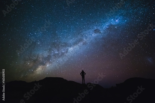 Landscape with Milky Way. Night sky with stars and silhouette of a standing woman on the mountain. © Guilherme