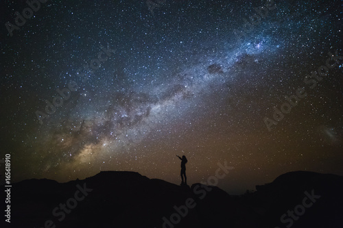 Landscape with Milky Way. Night sky with stars and silhouette of a standing woman on the mountain.