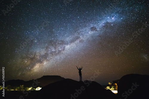 Landscape with Milky Way. Night sky with stars and silhouette of a standing woman on the mountain.