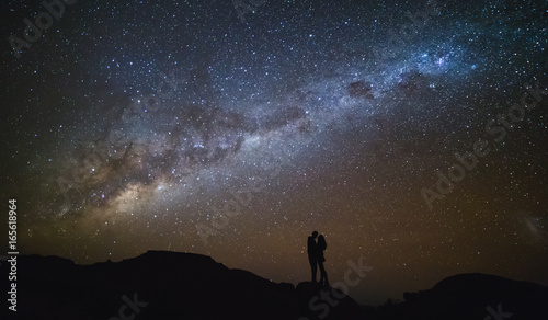 Landscape with Milky Way. Night sky with stars and silhouette of a couple kissing on the mountain.