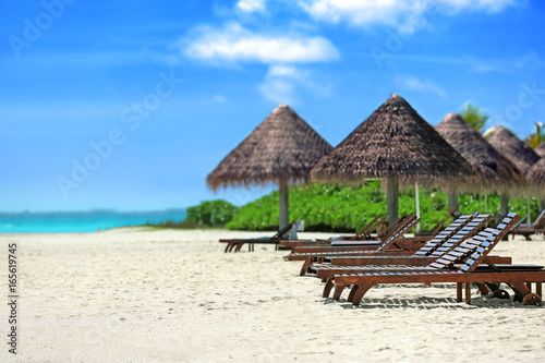 View of tropical beach with sun loungers on summer day