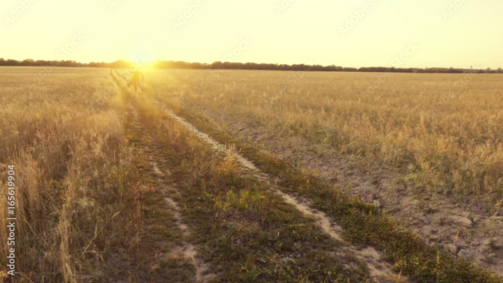 Crazy businessman runs skipping along a country road near a wheat field, waving his jacket in slow motion Crazy businessman runs skipping along a country road near a wheat field, waving his jacket in slow motion