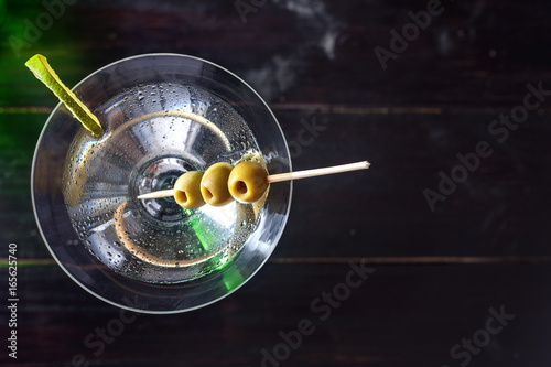 Glass of martini with olives and lime over a wooden table