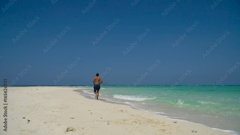 Man running along beach. Fitness sports runner man jogging on beach. Handsome young fit sporty male athlete running outside on beautiful beach training. 4K video. Man running along beach. Fitness sports runner man jogging on beach. Handsome young fit sporty male athlete running outside on beautiful beach training. 4K video.