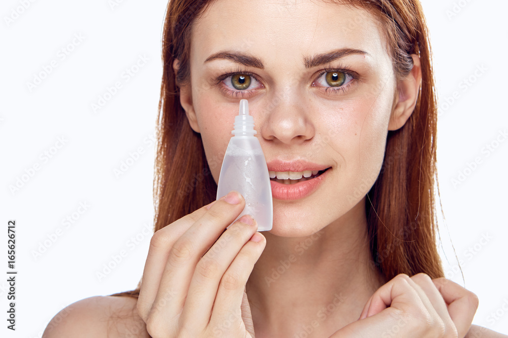 Beautiful young woman on white isolated background holds drops for eyes Beautiful young woman on white isolated background holds drops for eyes