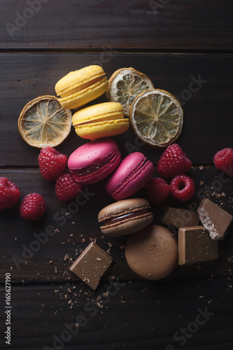 Group of colorful macarons with their ingredients over a wooden table