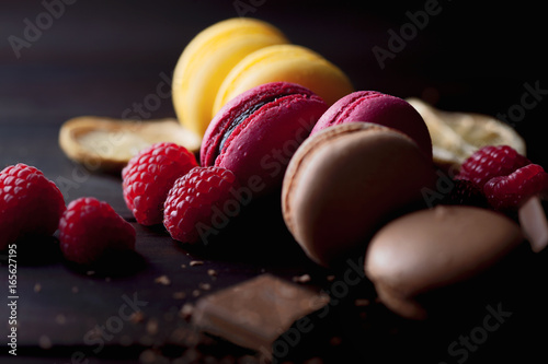 Group of colorful macarons with their ingredients over a wooden table