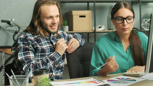 Business man and business woman in the glasses talking about future business project while sitting at the table in the modern office. photo