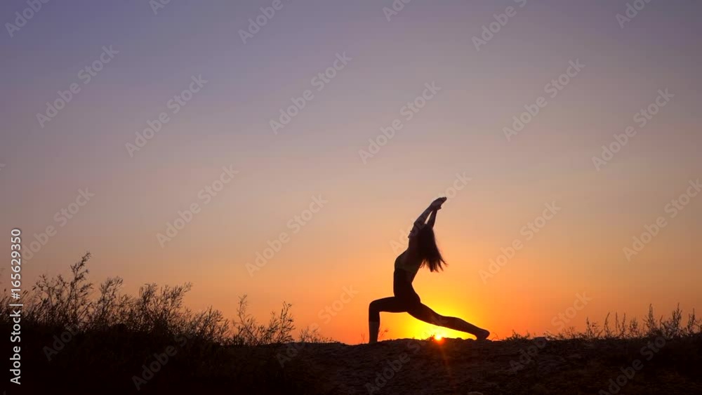 Silhouette young woman practicing yoga on the beach above sea at amazing sunset. fitness, sport, yoga and healthy lifestyle concept. Slow motion. Silhouette young woman practicing yoga on the beach above sea at amazing sunset. fitness, sport, yoga and healthy lifestyle concept. Slow motion.