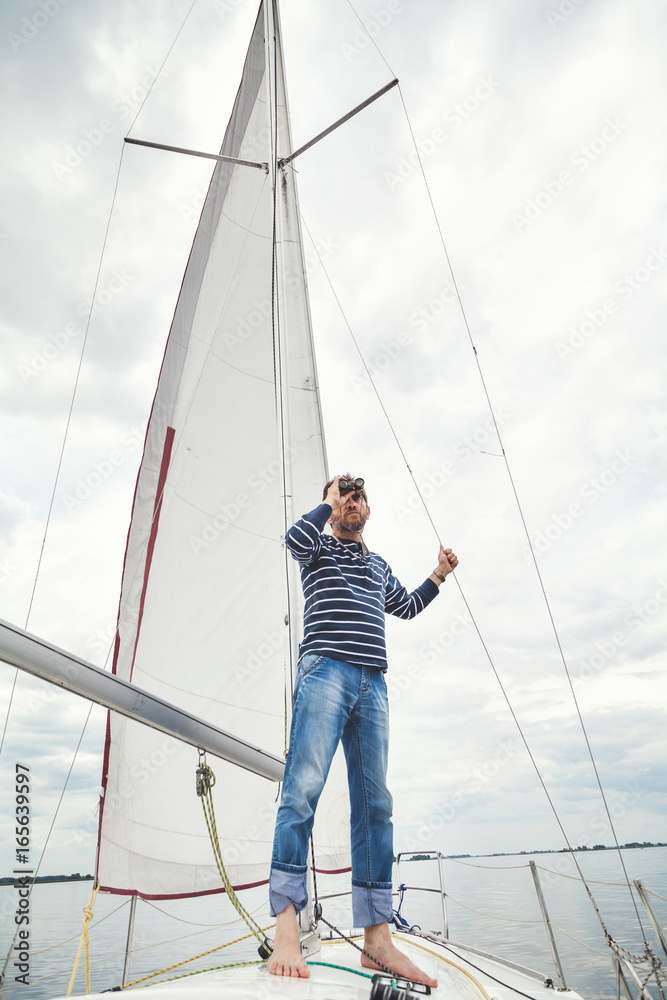 man in striped shirt looking through binoculars sailing yacht man in striped shirt looking through binoculars sailing yacht