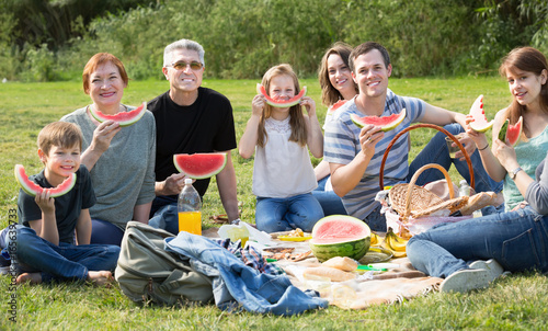 Family with kids talking and eating watermelon
