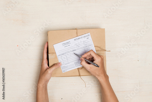 Top view of deliveryman making notes in "return to vendor" delivery receipt at table