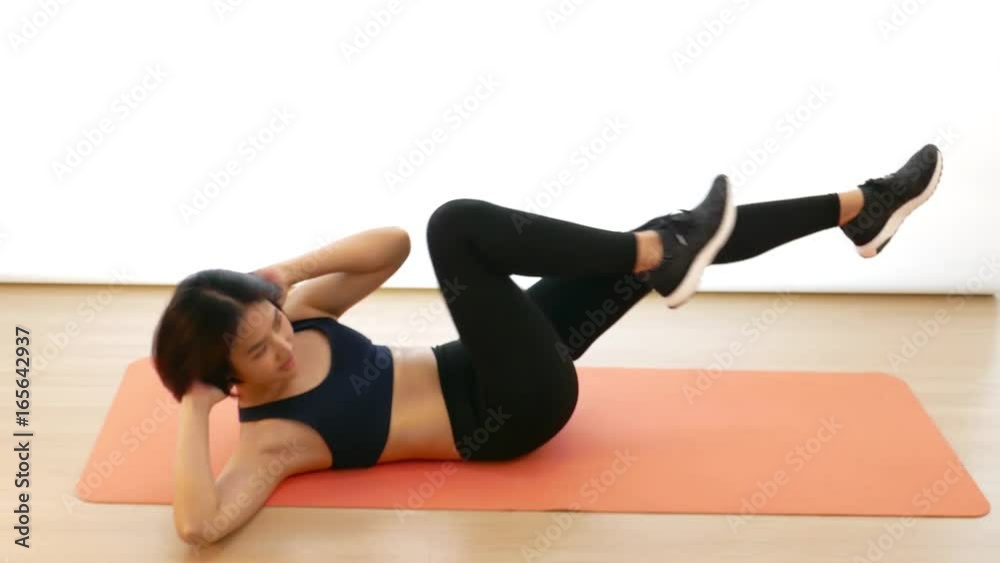 Pretty Thai Asian girl is doing bicycle crunch sit-up with elbow on the head cardio workout exercise in white background in fitness show concept Pretty Thai Asian girl is doing bicycle crunch sit-up with elbow on the head cardio workout exercise in white background in fitness show concept