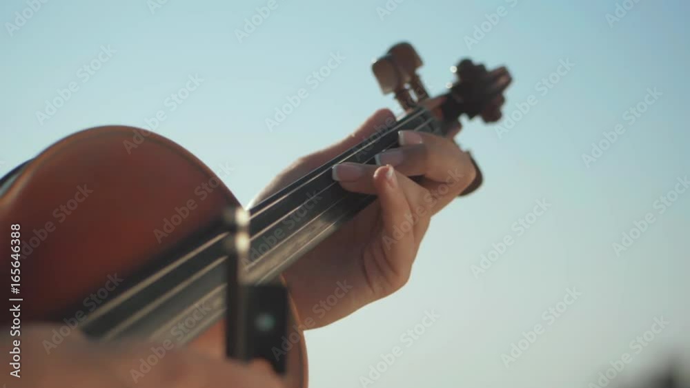 Girl violinist playing the violin outdoors. Green leaves backgound. Close up. Musician playing. Slow motion. Girl violinist playing the violin outdoors. Green leaves backgound. Close up. Musician playing. Slow motion.