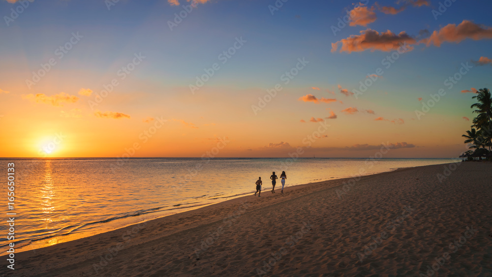 Thtree silhouette running on the beach at sunset in Mauritius.