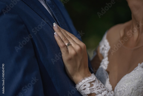 Young  beautiful bride holding her left hand with the ring on groom s chest.