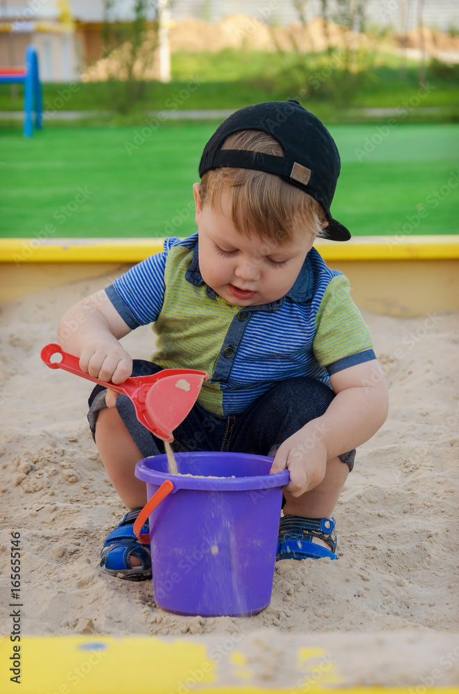Charming cute boy playing in the sandbox on the playground Charming cute boy playing in the sandbox on the playground