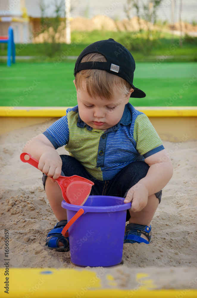 Charming cute boy playing in the sandbox on the playground Charming cute boy playing in the sandbox on the playground