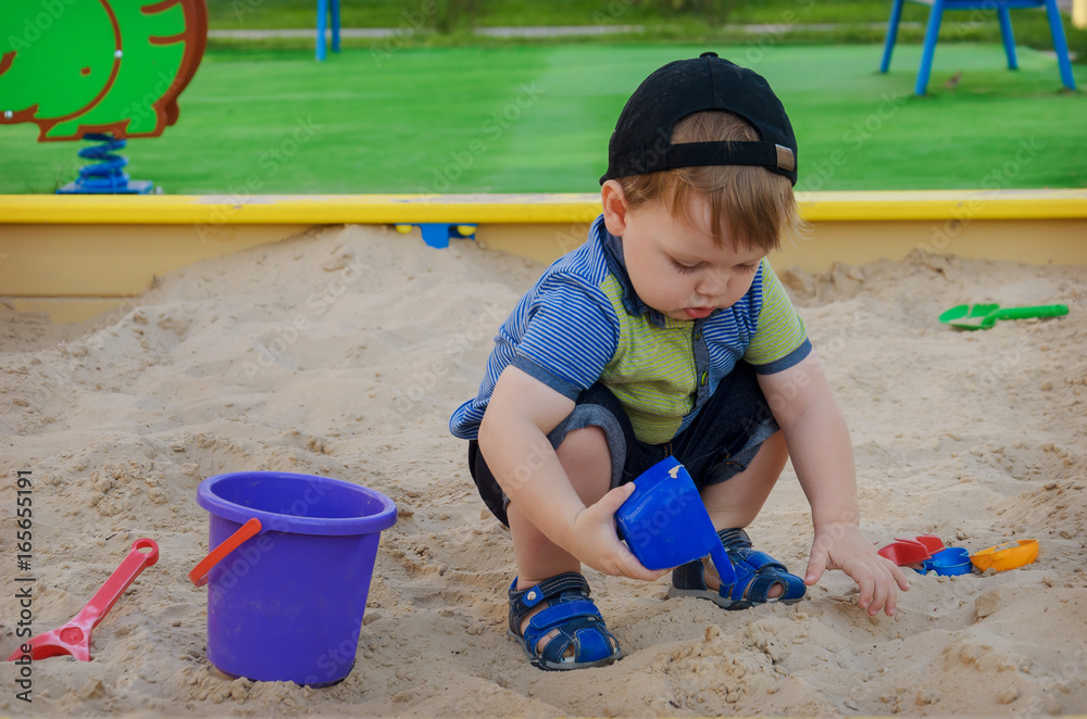 Charming cute boy playing in the sandbox on the playground Charming cute boy playing in the sandbox on the playground