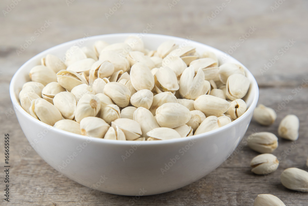 Pistachio nuts in a cup on wooden background. Pistachio nuts in a cup on wooden background.