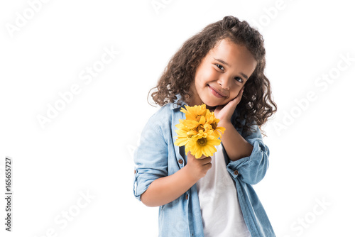 happy african american girl holding yellow flowers and smiling at camera isolated on white