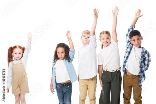multiethnic group of children raising hands and looking at camera isolated on white