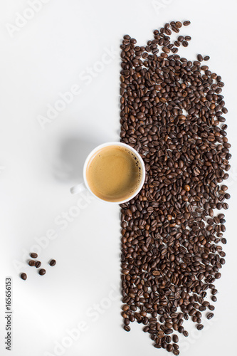 top view of cup of coffee and scattered coffee beans isolated on white
