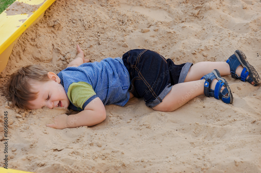 Charming cute boy playing in the sandbox on the playground Charming cute boy playing in the sandbox on the playground