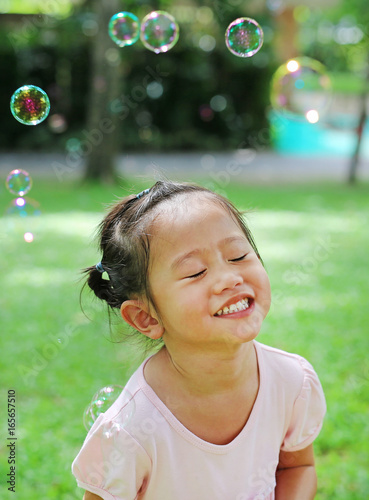 Cute little girl playing bubble in the garden.
