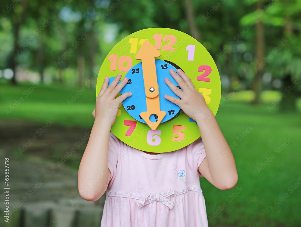 Φωτογραφία Little child girl showing up 6 O'clock round toy clock in the garden