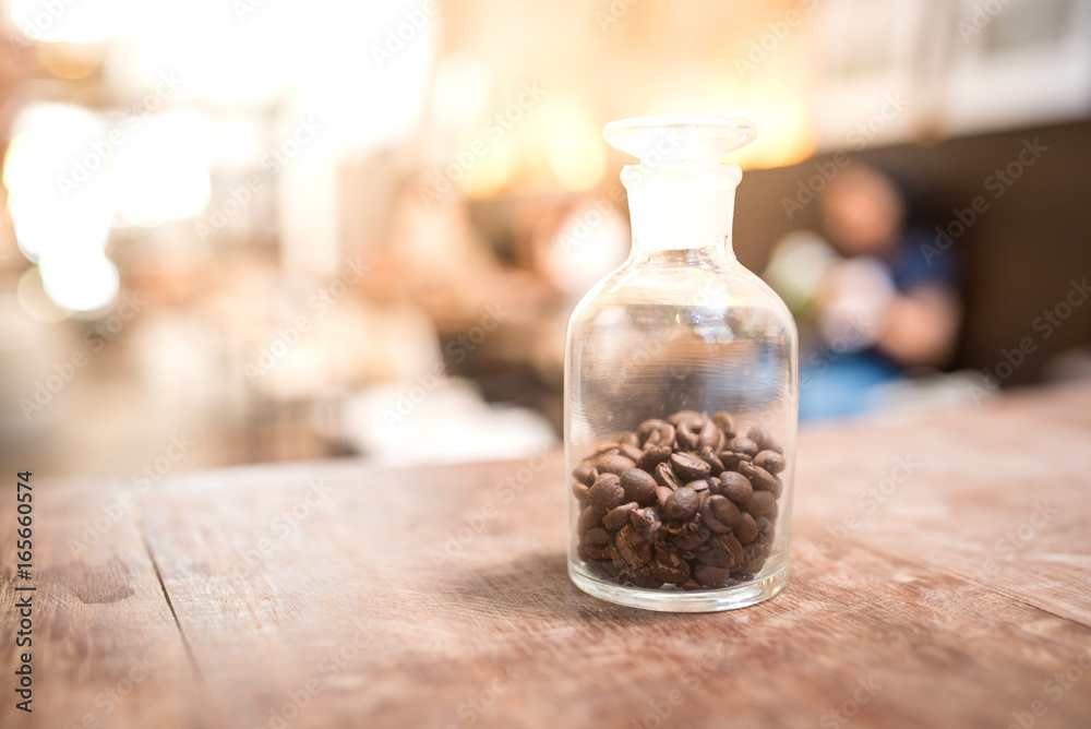 Roasted coffee beans A small glass jar on a wooden table.