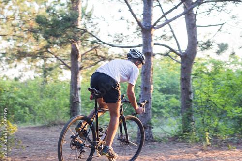 Young athlete riding on his professional mountain or cyclocross bike in the forest  © serejkakovalev