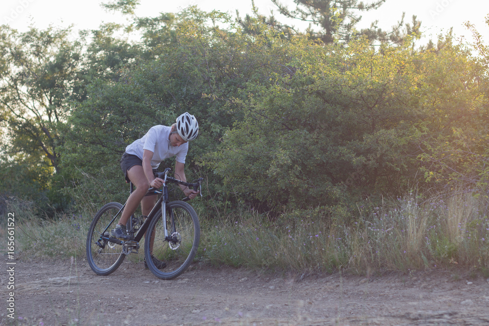 Male in helmet and sportswear on his cyclocross bike, riding on the country roads 