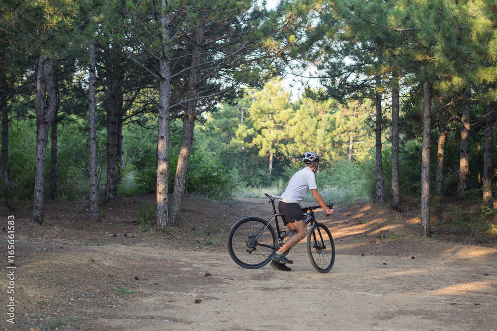 Young athlete riding on his professional mountain or cyclocross bike in the forest 