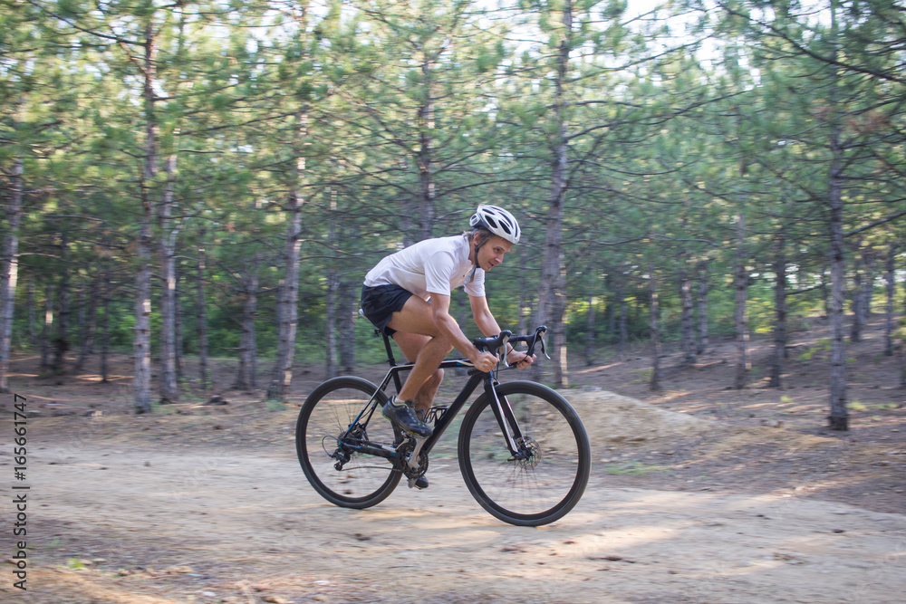 Young athlete riding on his professional mountain or cyclocross bike in the forest 