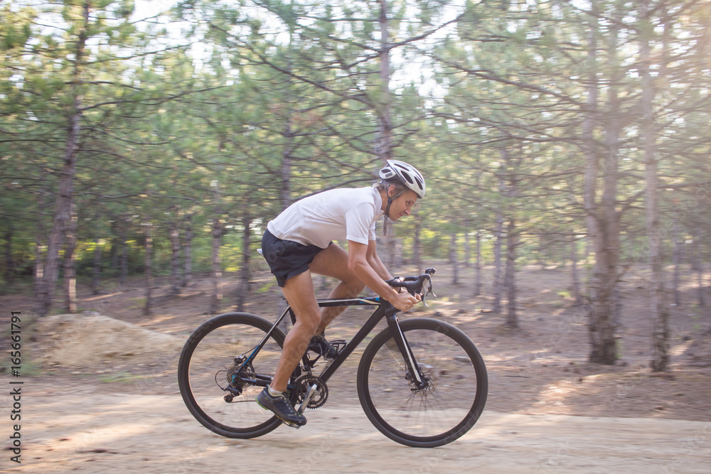 Young athlete riding on his professional mountain or cyclocross bike in the forest 