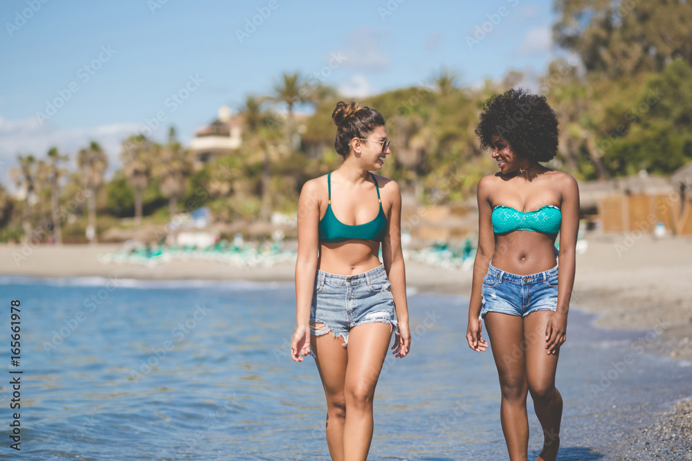 Two happy female friends walking in water chatting Two happy female friends walking in water chatting