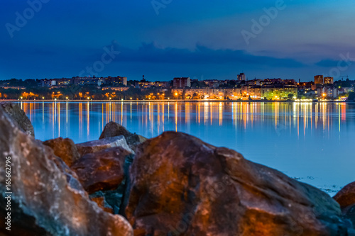 Fototapeta Naklejka Na Ścianę i Meble -  The lights of the Eastern European city are reflected in the lake.