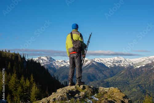 Traveler photographer stands on a rock, with tripod in hands