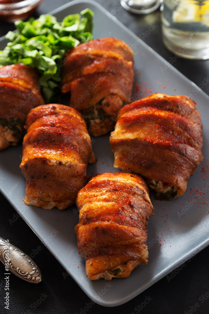 Stuffed chicken rolls in bacon on grey tray