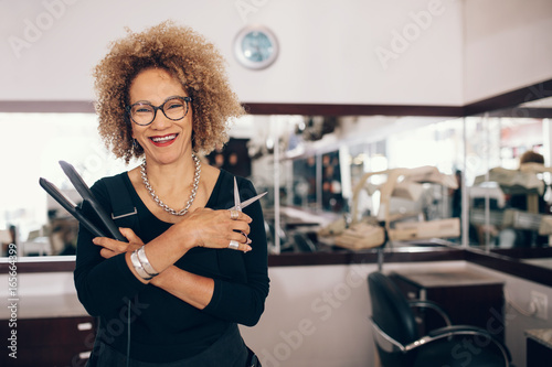 Tableau sur toile Female hairdresser at the salon holding hairdressing tools
