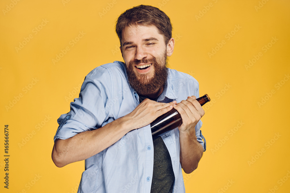 Man with a beard on a yellow background holds a bottle of beer, alcohol Man with a beard on a yellow background holds a bottle of beer, alcohol