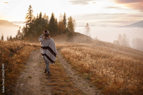 фотографія Young woman over the clouds in the valley looking at calm sunrise