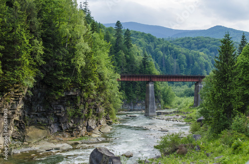 mountain river with a rapid current of rocks and a bridge