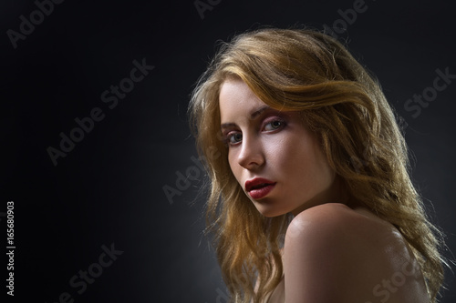 Attractive blonde woman on dark background .