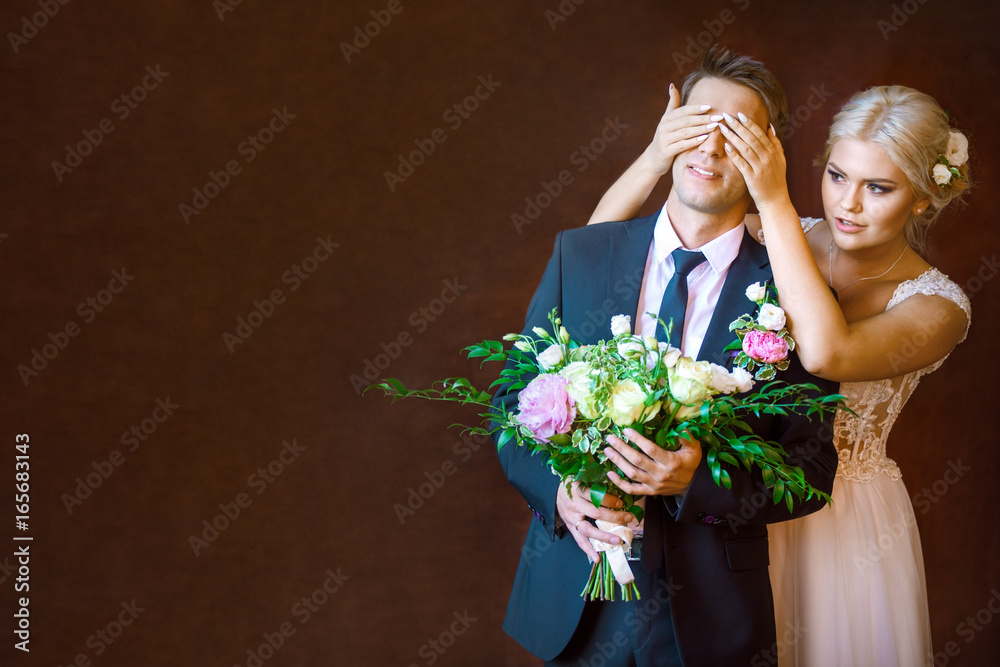 Fototapeta premium the bride closes to groom's eyes in the studio