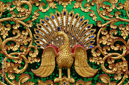 Green wall with patterned of leaf and peacock in gold for a background.