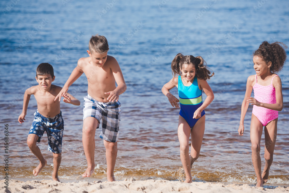 multicultural happy children in swimsuits running at seaside together multicultural happy children in swimsuits running at seaside together
