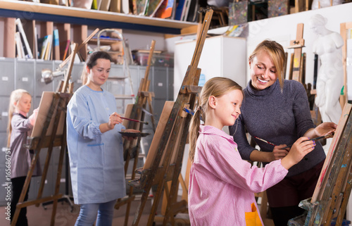 Female teacher assisting student during painting
